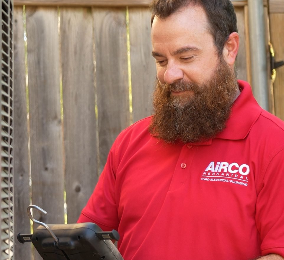 An AiRCO Mechanical technician servicing an air conditioner