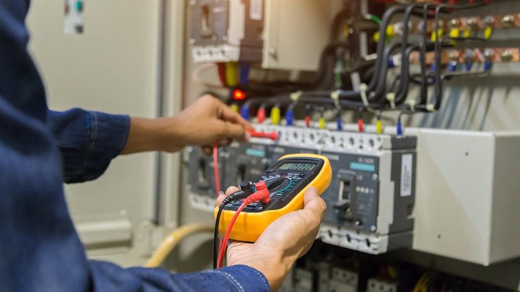 An electrician testing a breaker panel with a multimeter